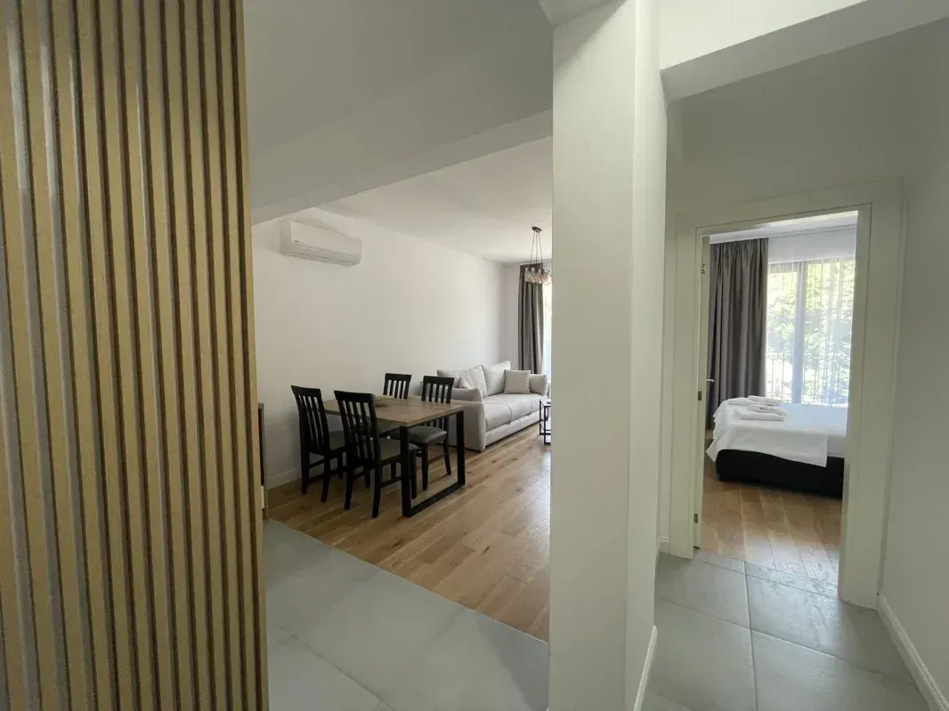 View from the hallway towards the living room with a dining area and a bedroom.
