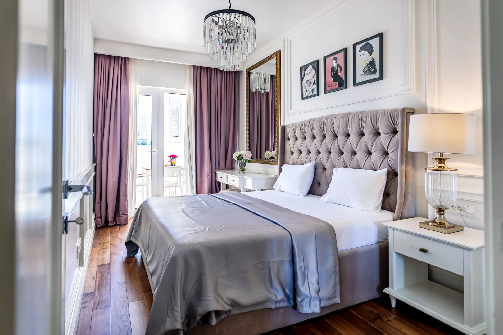Modern bedroom with a double bed, elegant chandelier, and access to the terrace.