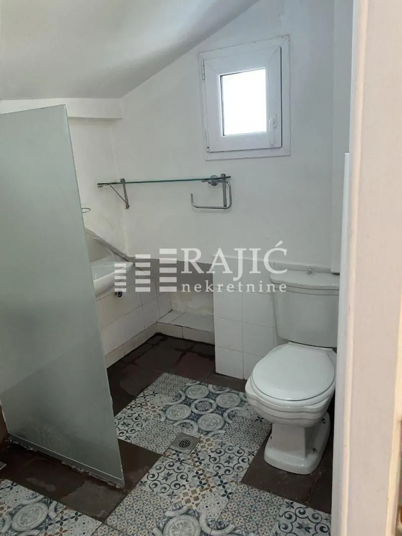 Smaller bathroom with a toilet, shower enclosure and window.