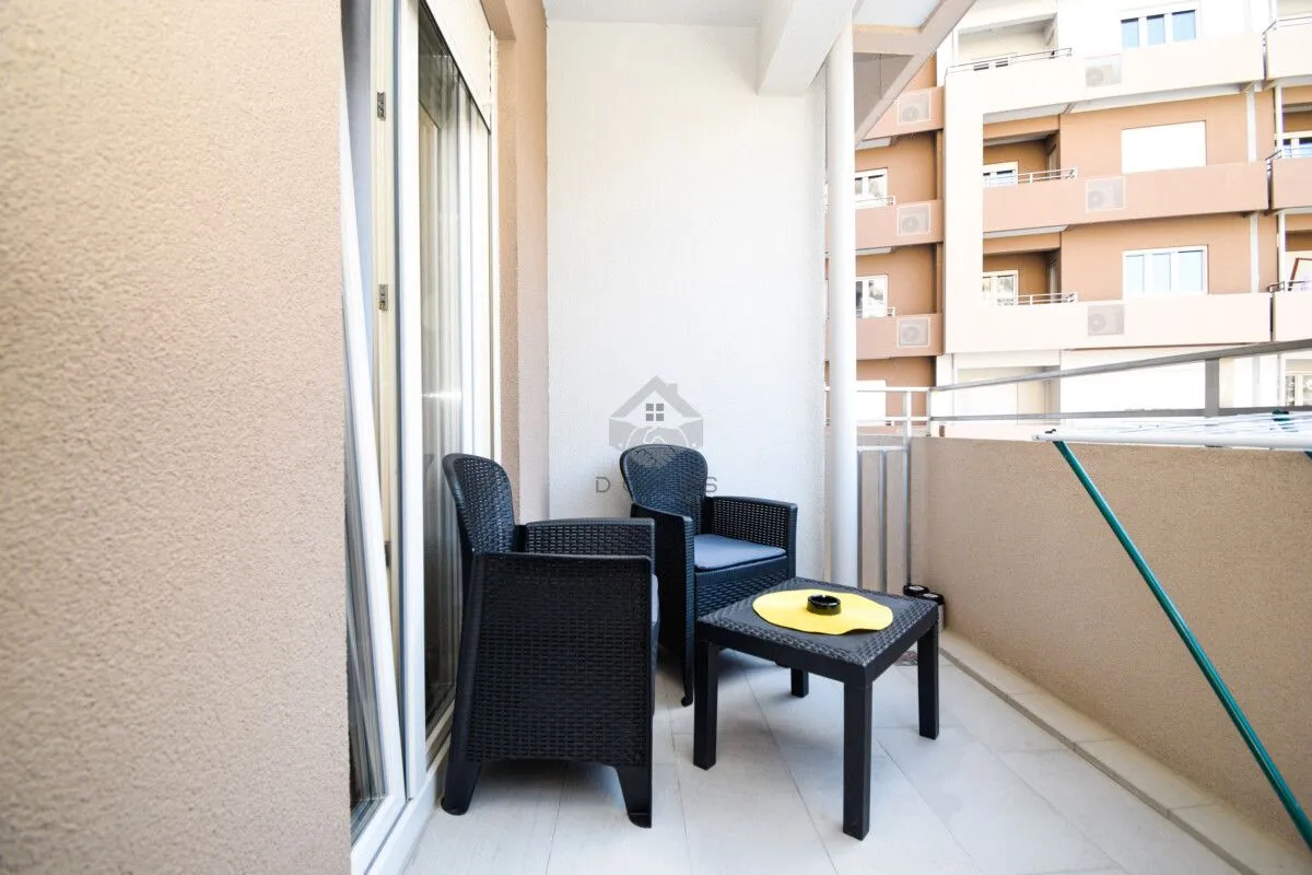 Furnished balcony with seating set and a view of surrounding buildings.