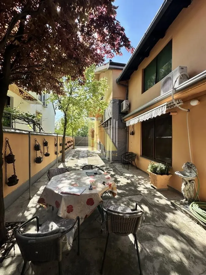 Popločano dvorište sa garniturom za sedenje i pogledom na fasadu kuće.