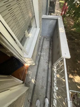 Pogled odozgo na balkon sa metalnom ogradom i prozorom sa roletnama. - image 11