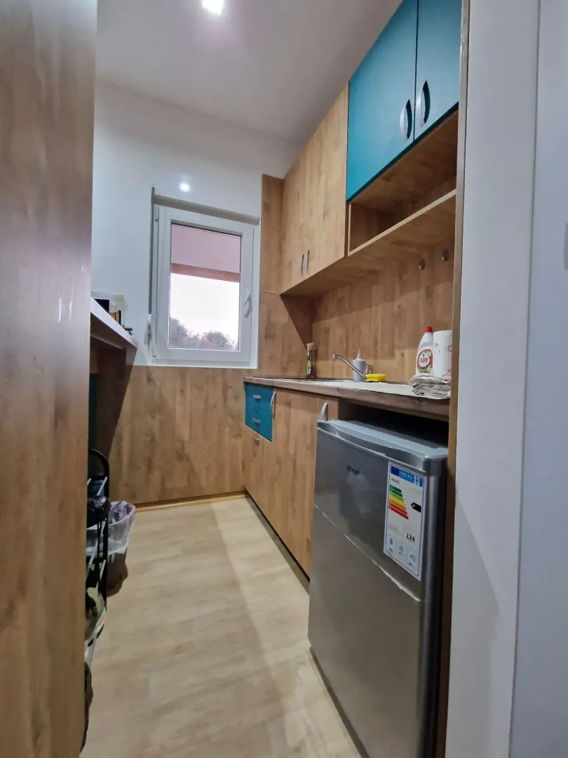Smaller kitchen with wooden units, sink, and refrigerator.