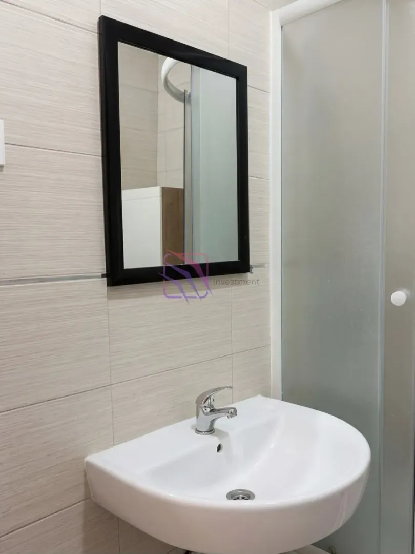 Bathroom with a sink, black-framed mirror, and a shower cabin.