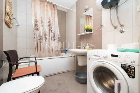 Bathroom equipped with a bathtub, washbasin, washing machine, and toilet bowl. - image 3