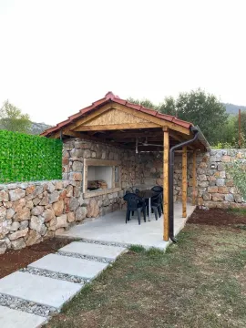 Covered gazebo with a built-in barbecue and seating set in the yard. - image 12