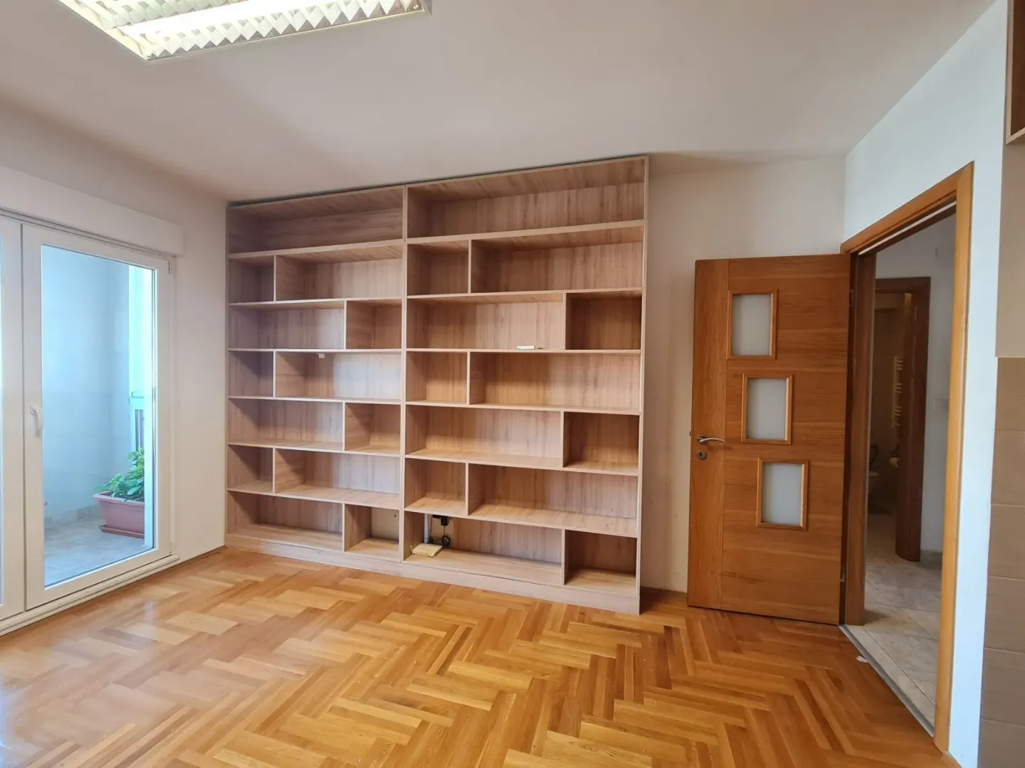 A room with a wooden bookshelf and parquet flooring.