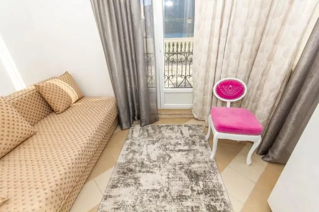 Living room with a sofa, rug, and brightly colored chair near the balcony door.