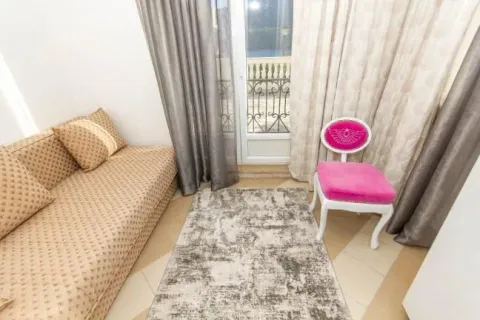 Living room with a sofa, rug, and brightly colored chair near the balcony door. - image 6