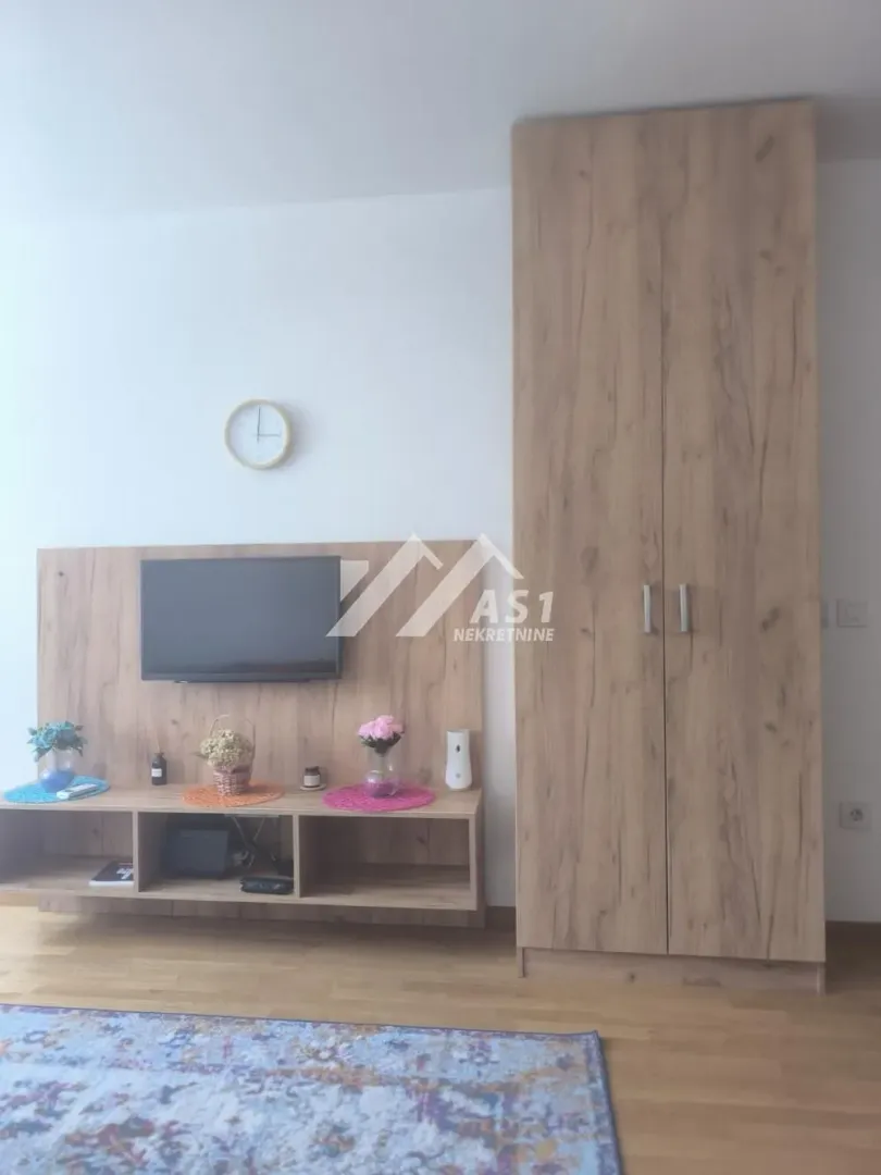 Dnevni boravak sa drvenom komodom za TV i garderoberom.