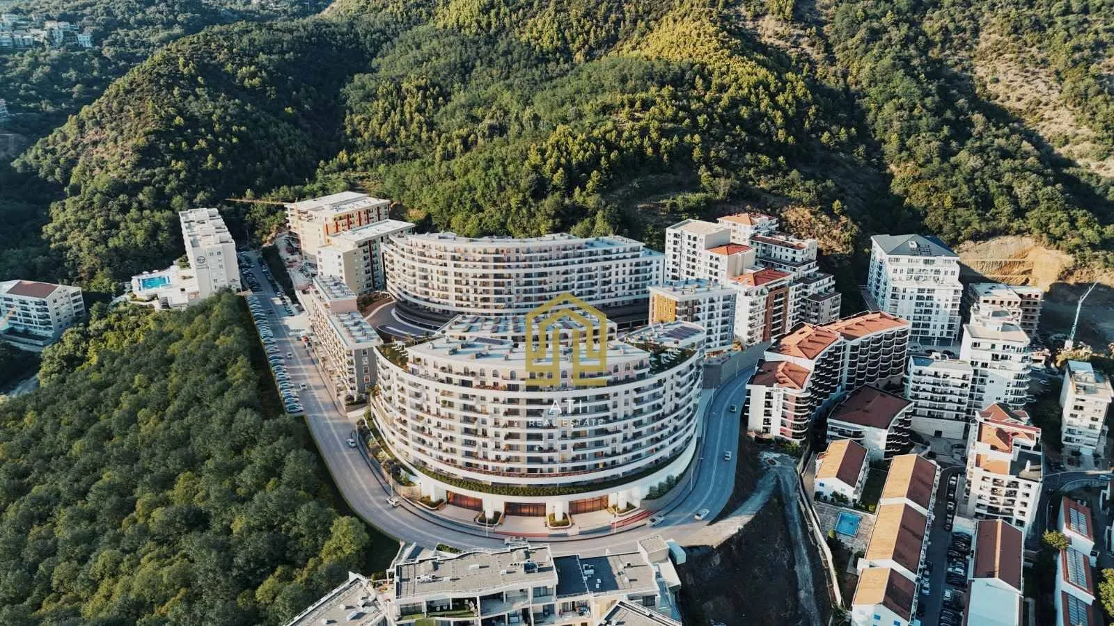Pogled iz vazduha na moderne stambene zgrade okružene zelenilom.