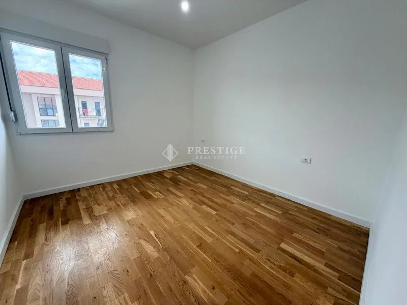 Prazna soba sa drvenim podom i bijelim zidovima.