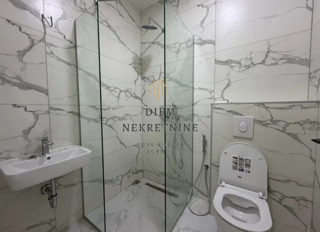 Modern bathroom with a glass shower enclosure and marble-style tiles.