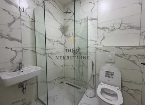 Modern bathroom with a glass shower enclosure and marble-style tiles. - image 6
