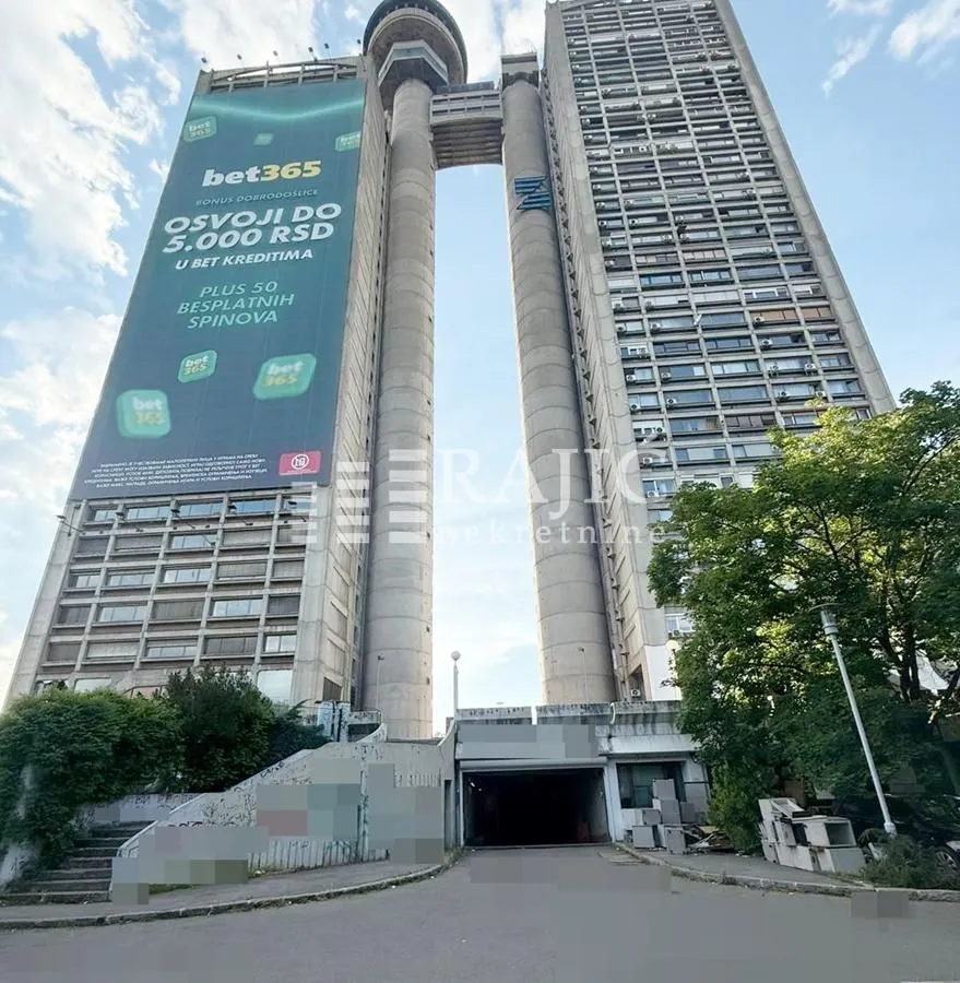 Exterior view of a tall residential and commercial building with an entrance drive.