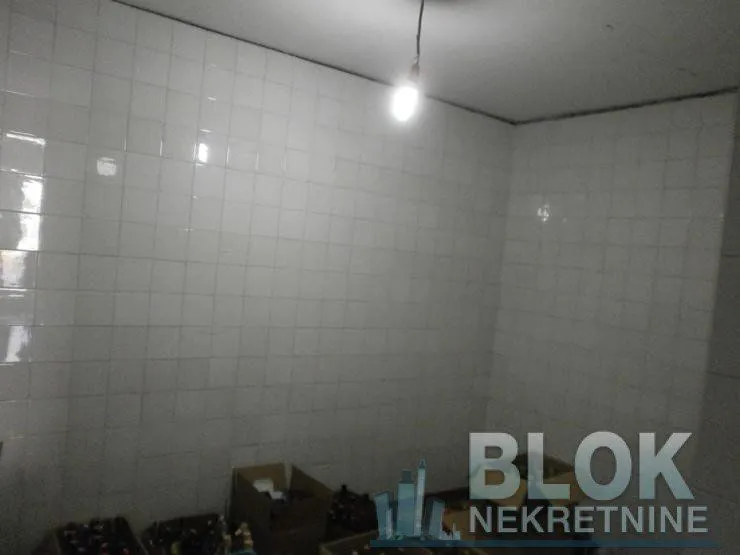 Small room with white wall tiles and boxes on the floor.