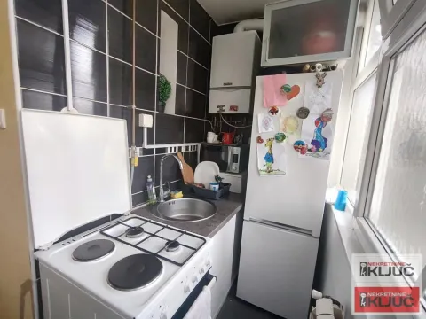 Manja kuhinja sa šporetom, frižiderom i tamnim zidnim pločicama. - image 7