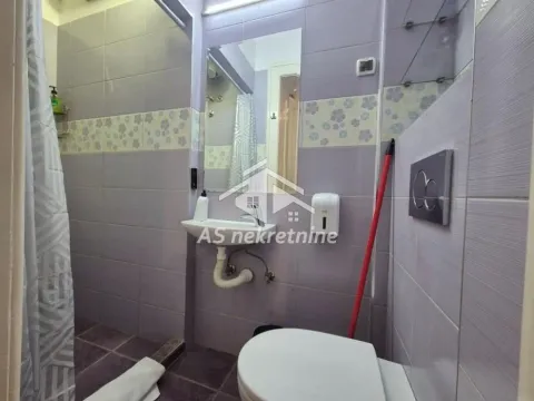 Small bathroom tiled in purple with a shower cabin, washbasin, and toilet. - image 19