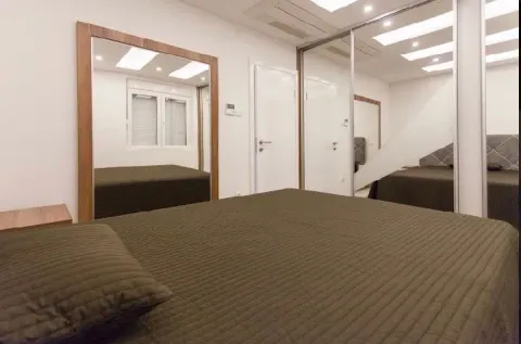 Furnished bedroom with a double bed and a large mirror. - image 10