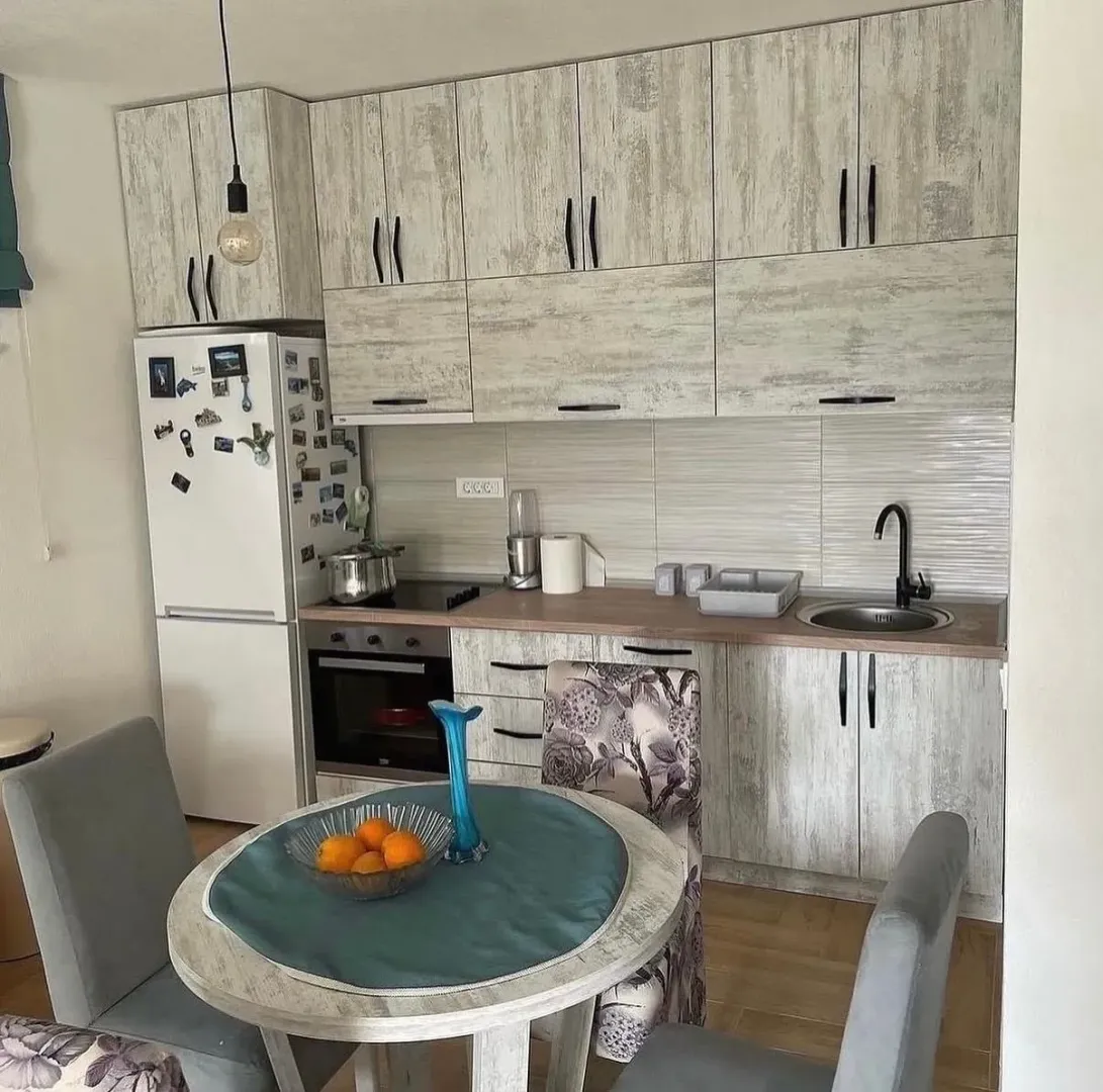 Small kitchen with light-colored cabinetry and a dining table in the foreground.