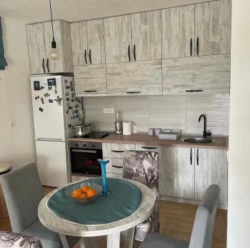 Small kitchen with light-colored cabinetry and a dining table in the foreground. - image 3