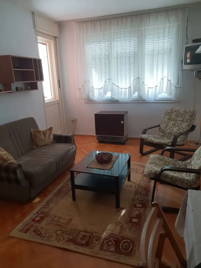 Jednostavna dnevna soba sa kaučem, foteljama i stočićem.