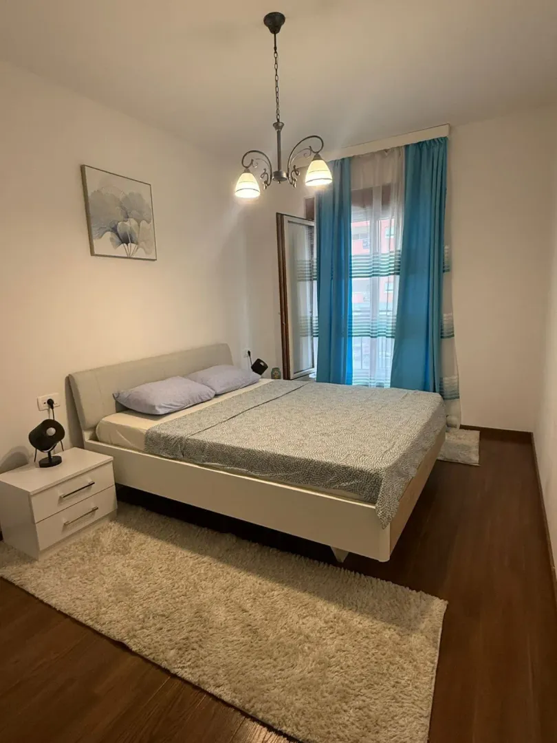 A bright bedroom with a double bed and blue curtains.