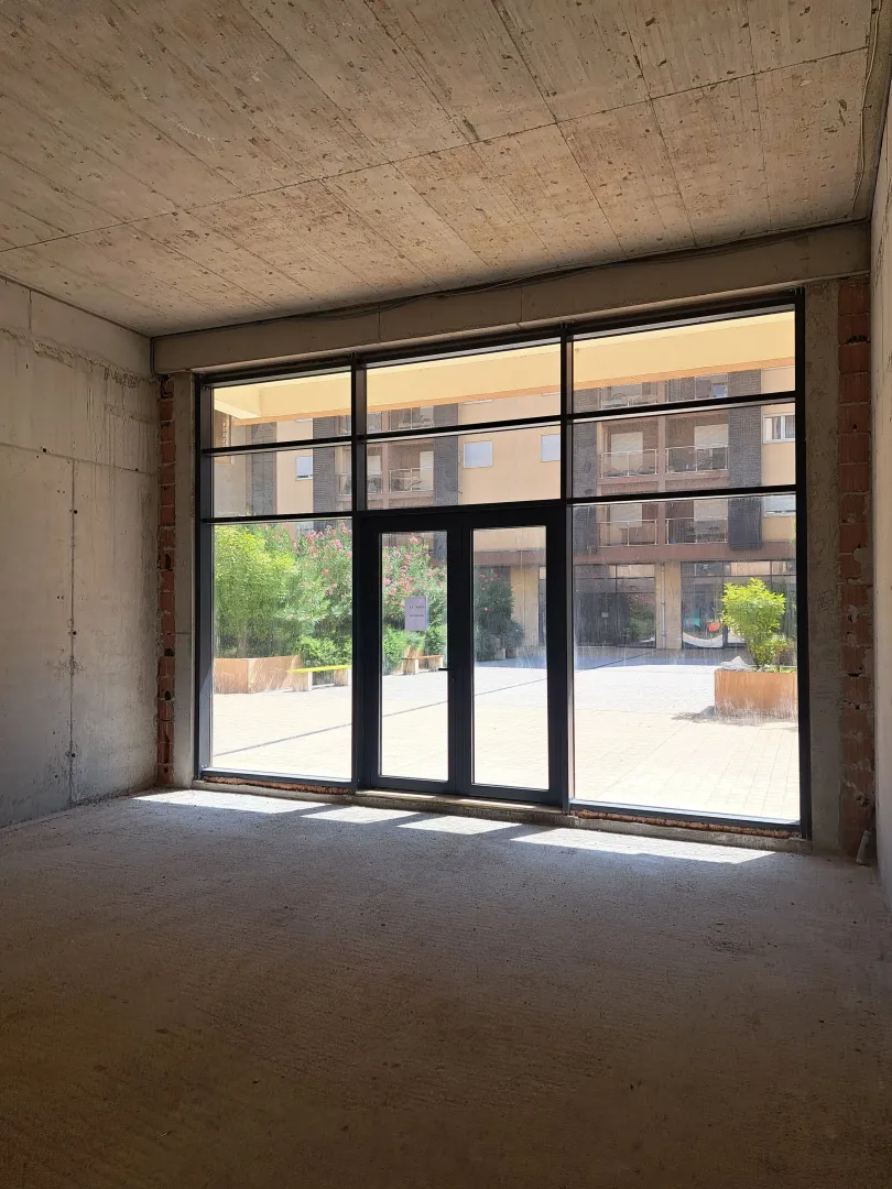 Unfinished commercial space with a large glass storefront and a courtyard view.