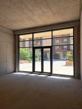 Unfinished commercial space with a large glass storefront and a courtyard view. - image 4
