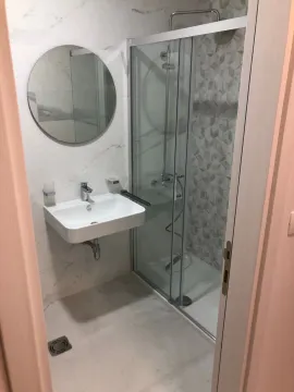 Moderne kupatilo sa umivaonikom, tuš kabinom i okruglim ogledalom. - image 2