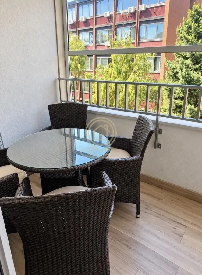 Natkriveni balkon sa stolom i pletenim stolicama za sedenje.