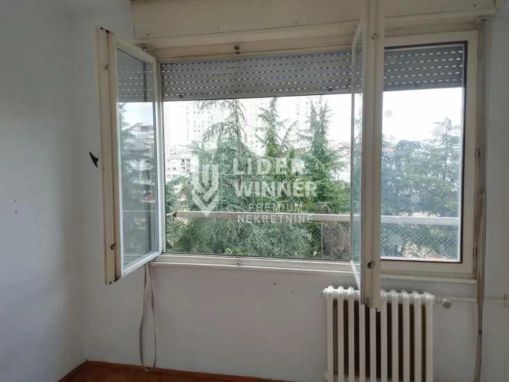 Empty room with an open window and a view of trees.