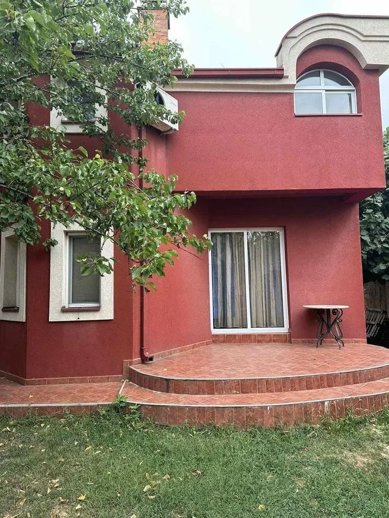 Rear view of the house with a red facade, patio, and yard.