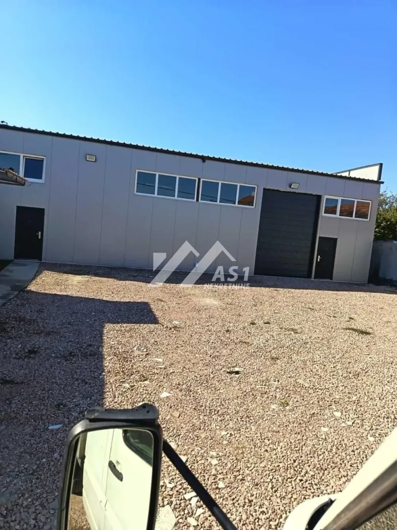 View of the exterior of an industrial building with a large yard and loading doors.
