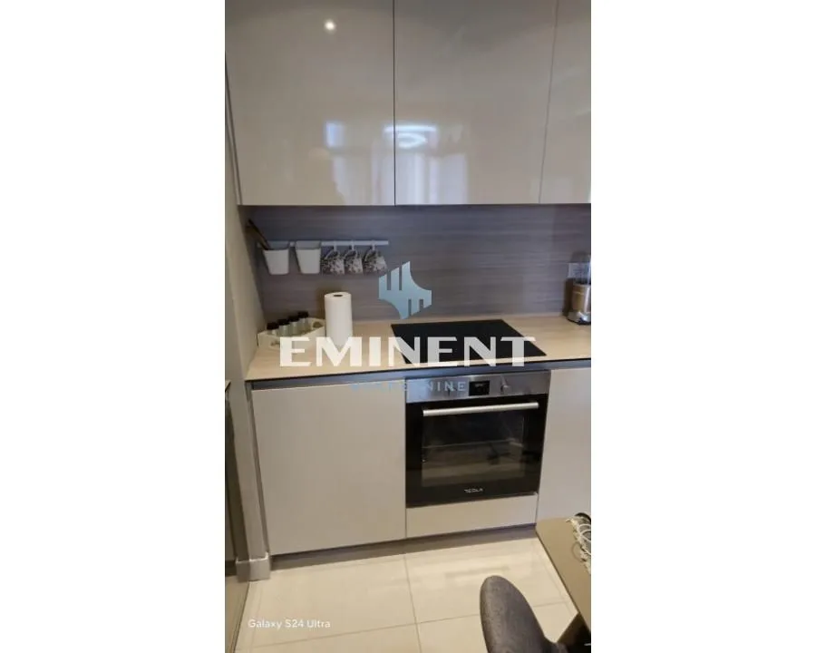 Part of the kitchen with a built-in oven and light-toned cabinets.