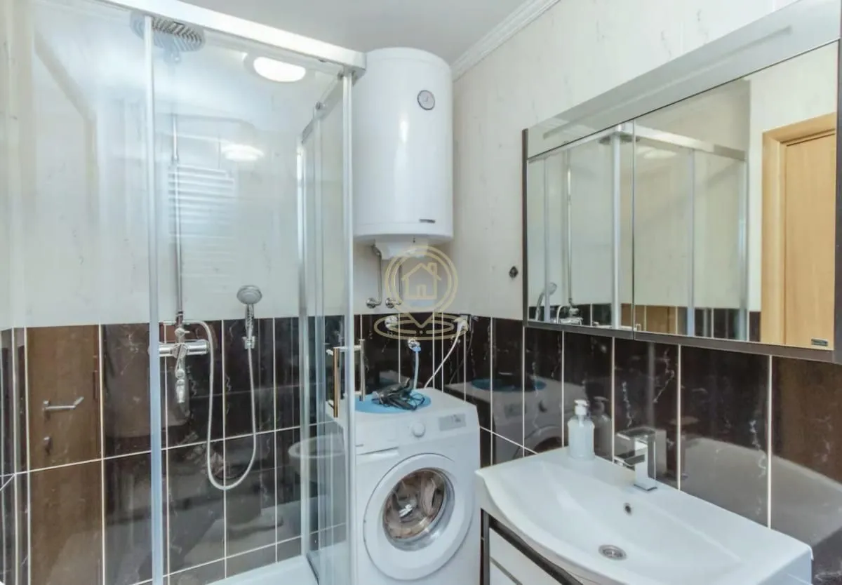 Bathroom equipped with a shower cabin, washbasin, washing machine, and water heater.