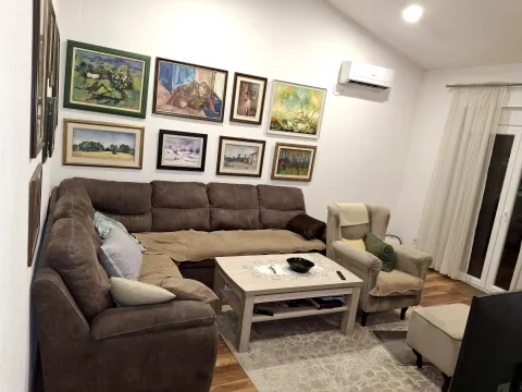 Dnevna soba sa ugaonom garniturom, foteljom i umjetničkim slikama na zidu. - image 7