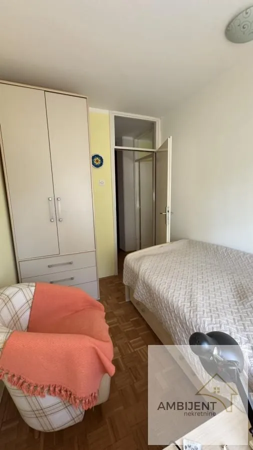 Small bedroom with a bed, wardrobe, and armchair.