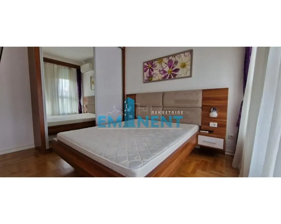 Furnished bedroom with a double bed, wardrobe, and wooden flooring.