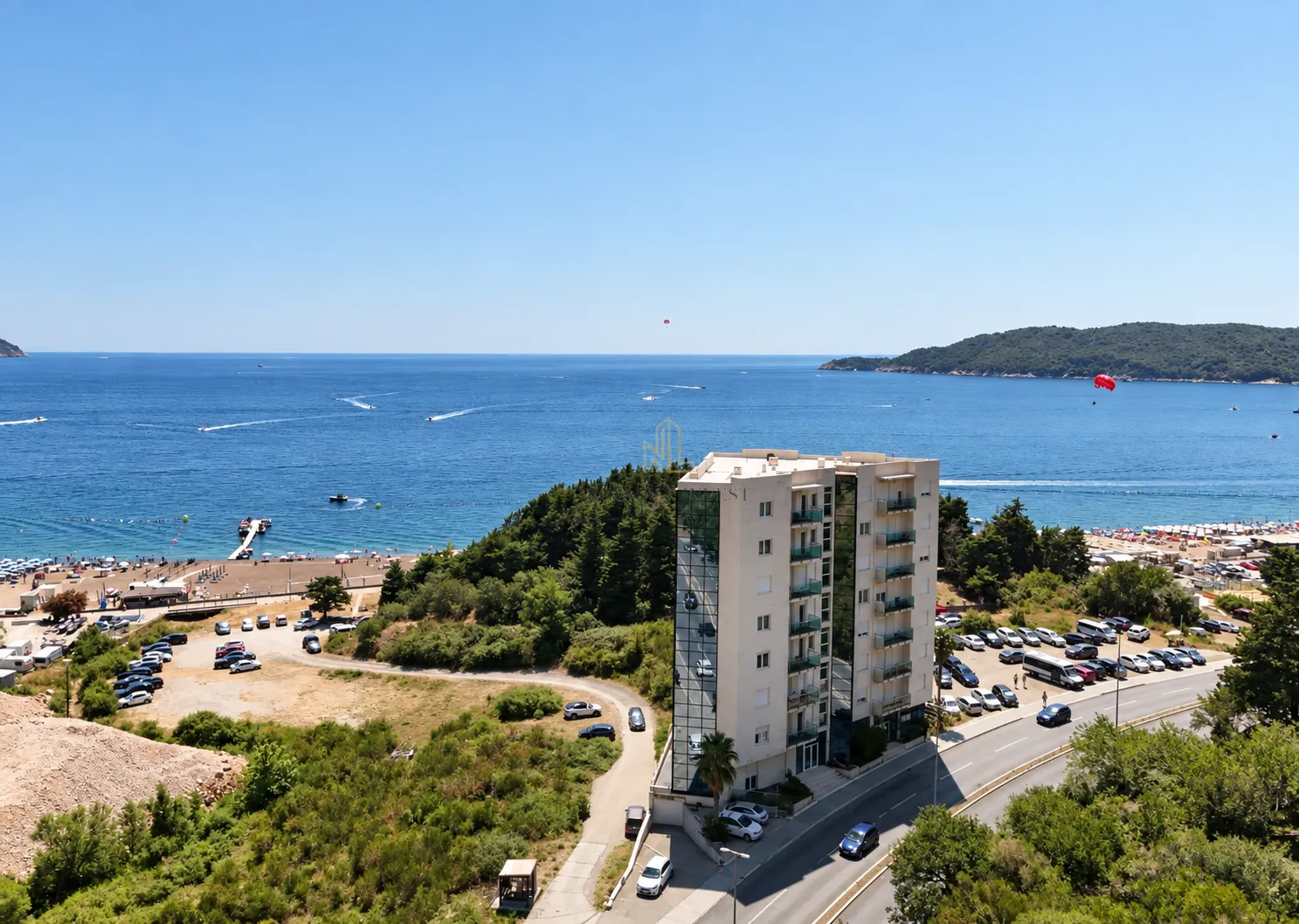 Pogled sa prozora na more, plažu i okolne zgrade.