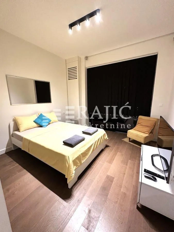 Furnished bedroom with a double bed and wooden flooring.