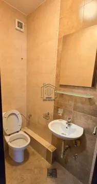Manje kupatilo obloženo bež pločicama sa wc šoljom, umivaonikom i ogledalom. - image 4