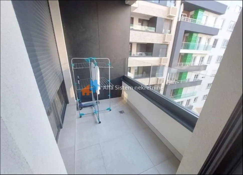 Small tiled balcony with a glass railing and a laundry drying rack.