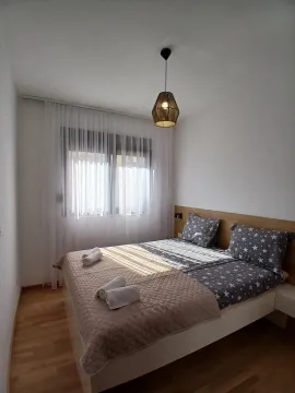 Svijetla spavaća soba sa bračnim krevetom i prozorom prekrivenim zavjesama. - image 3