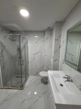 Moderne kupatilo sa tuš kabinom, umivaonikom i bijelim mermernim pločicama. - image 6