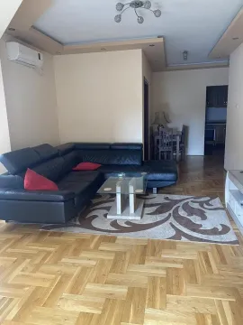 Living room with a black sectional sofa, coffee table, and parquet flooring. - image 6