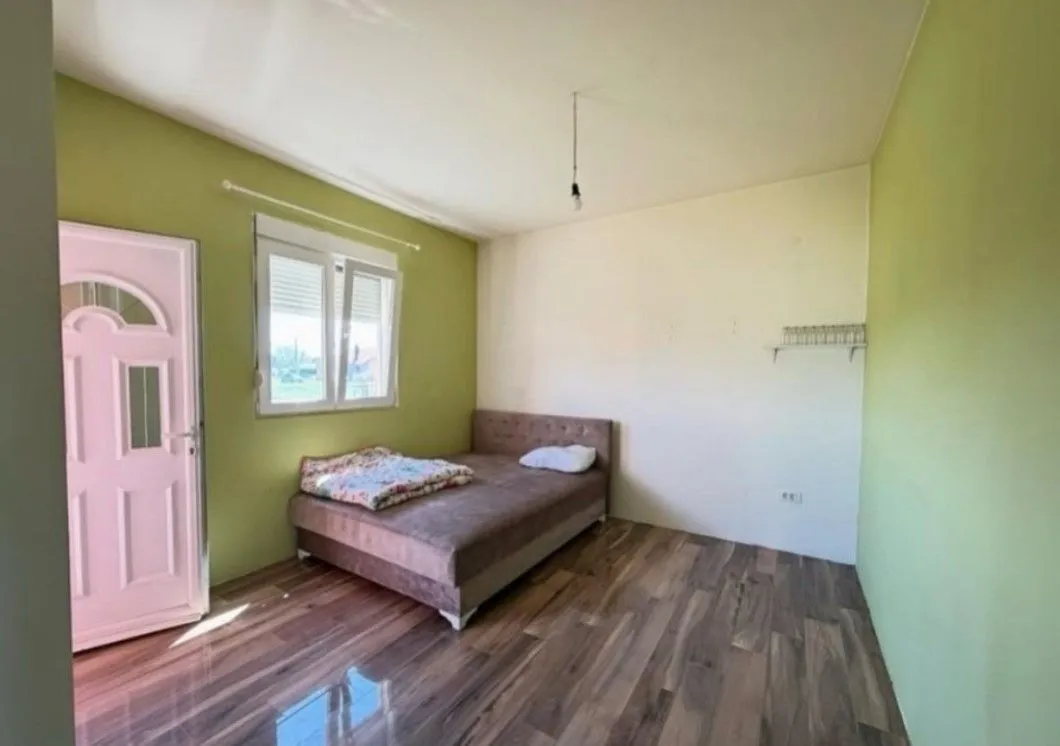 Bedroom with a double bed, a window, and light-colored walls.