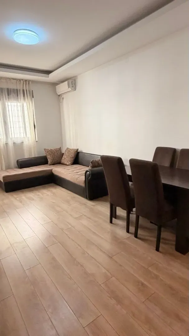 Dnevni boravak sa ugaonom garniturom i trpezarijskim stolom.