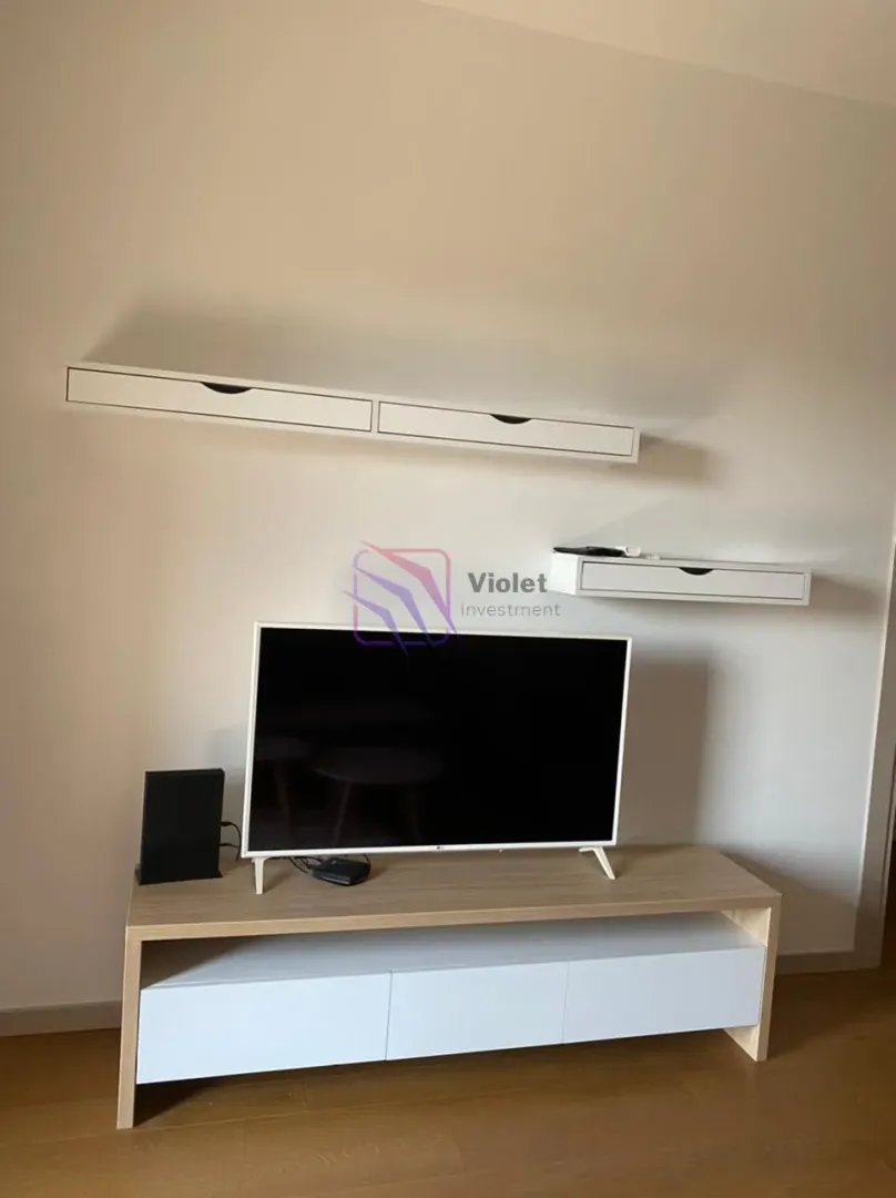 Living room with a television and mounted white wall shelves.