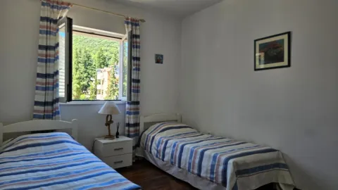 Spavaća soba sa dva kreveta i prozorom sa pogledom na zelenilo. - image 16